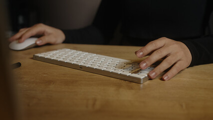 Close-up of female hands typing on a white keyboard on the table