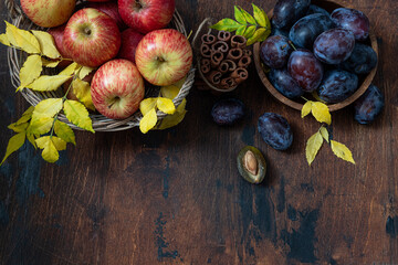 Fresh, ripe apples and plums with cinnamon sticks on a wooden table
