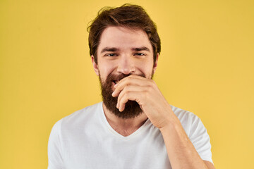 A man in a white t-shirt gestures with his hands lifestyle cropped view yellow background more fun