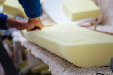Vertical shot of a furniture maker shaping an upholstery foam - obrazy, fototapety, plakaty