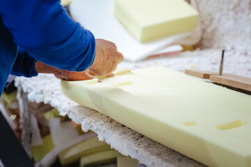 Vertical shot of a furniture maker shaping an upholstery foam