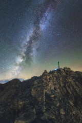 Climber stands still on the summit of Mt Olympus pointing the Milky Way Galaxy