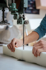 Vertical shot of a furniture maker cutting an upholstery foam using a foam cutter machine