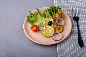 Light plate of greek salad near napkin and fork on gray concrete background. Copy space.