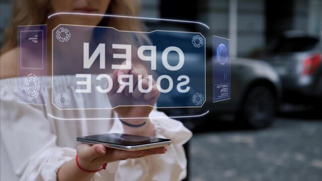 Unrecognizable blonde woman standing on the street interacts HUD hologram with text Open source. Girl in white clothes uses technology of the future mobile screen