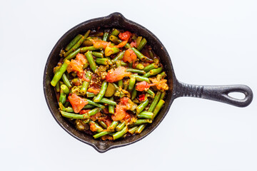 stewed green beans in a cast iron skillet on a white background
