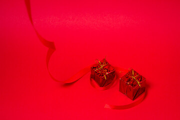 Red gift with a red ribbon on a red background. Holiday decorations. Christmas concept. 