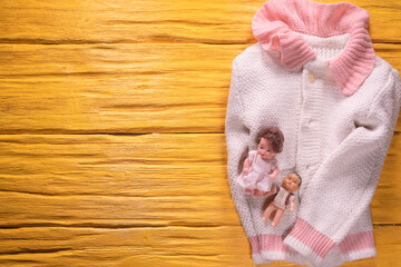 Old children toys and girl sweater on the wooden flat lay floor background.