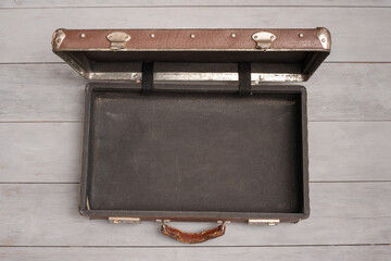 Retro style brown open empty suitcase on the wooden floor background.
