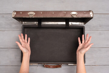 Woman is spreading by her hands over an empty suitcase. Missing clothing. Forgot to fold a clothes.