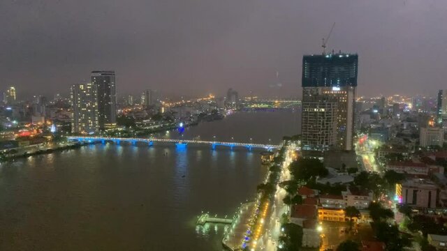 Time lapse video of night fall across the city of Da nang in Vietnam with a view of lights coming on the sky scrappers and beautiful bride over river Han
