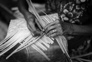 Black and white close up view of Balinese woman making a  traditional bamboo basket