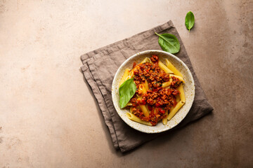 Overhead view of bolognese pasta in bowl on stone table