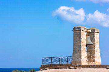 The bell of Chersonesos rises on the seashore in Crimea against the background of a blue sky on a summer sunny day.