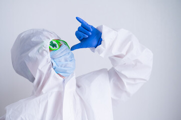A woman in a protective suit and mask and glasses for st patrick's day gestures booze. A...