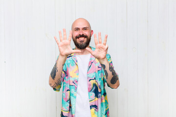bald man smiling and looking friendly, showing number nine or ninth with hand forward, counting down