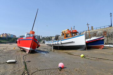 Boats on the sand in Tenby harbour at low tide. - 392476069