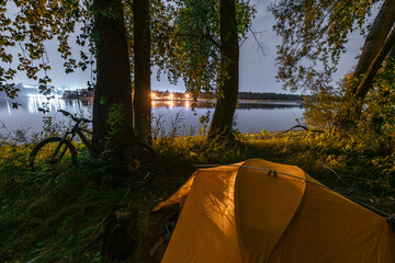 Evening Camping Landscape on Shore. Rest in the Forest by the River in a Tent. Traveling out of Town by Bike. Outdoor Lifestyle Concept