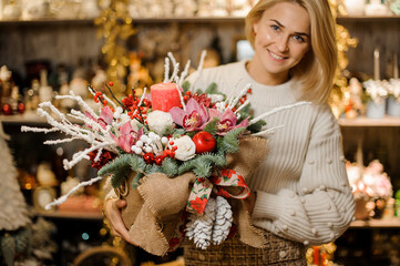 gorgeous large christmas arrangement decorated with candles in the hands of florist woman