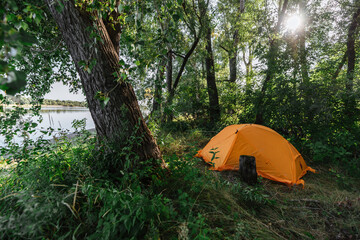 Morning Camping Landscape on Shore. Rest in the forest by the river in a tent. Traveling out of town. Outdoor lifestyle concept