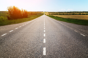Country asphalt road through agricultural fields on a sunny day. Logistics and transport companies background