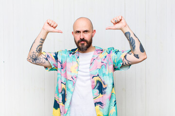 bald man feeling proud, arrogant and confident, looking satisfied and successful, pointing to self