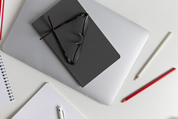 workspace on the table. notebook and diary with pencils. the notebook is on the laptop. business composition with glasses laptop and notepad. flat lay