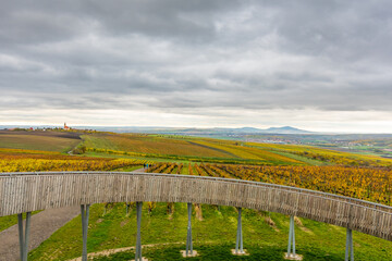 Fototapeta premium Lokout tower at Kobyli Vrch hill, South Moravia region - Czech republic. Wooden spiral construction near vineyards and church. Palava hills, famous wine area. Autumn weather, clouds after rain.