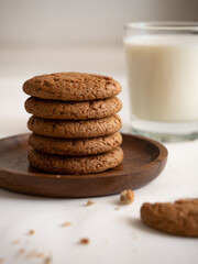 Oatmeal cookies in a wooden plate and a glass with milk on a white background
