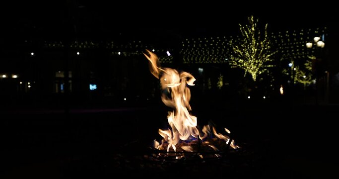 Holiday Night fire flames lights in background 4K. Christmas winter holiday season with decorations, warm fires and festive lights decorate public and home property.