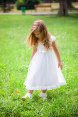 Fototapeta na wymiar Little girl on the lawn in a white dress