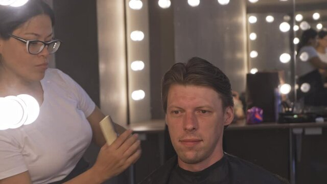 Assian hairdressers hands hold pieces. Master makes haircut with scissors. Client is sitting in chair and smiling. High quality 4k footage