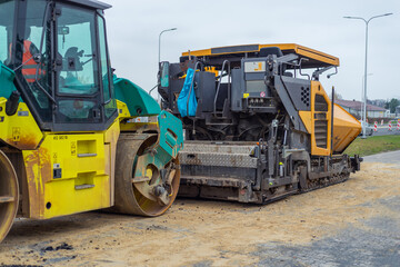 Fototapeta na wymiar Asphalt paver machine and steam road roller during road construction and repairing works, process of asphalting and paving, workers working on the new road construction site