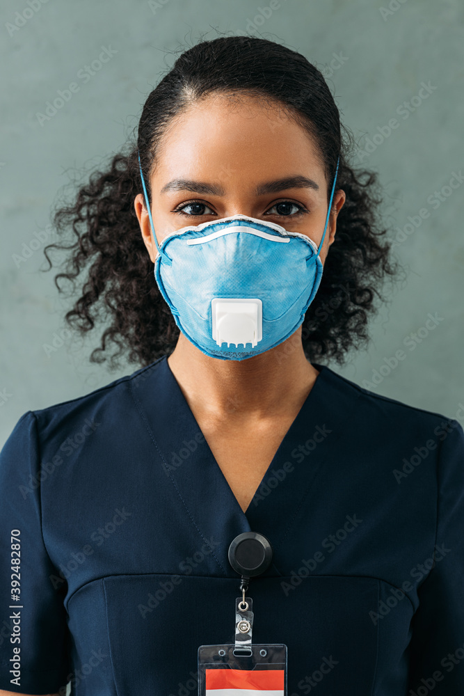 Wall mural Close up portrait of a female nurse wearing a respirator and looking at the camera