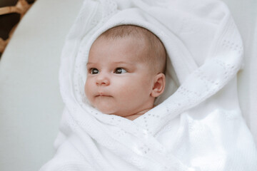 Adorable baby in a white sunny bedroom. Newborn baby is resting in bed. Family morning at home.