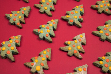 Christmas cakes in the form of Christmas trees are laid out in a pattern on a red background. Horizontal orientation