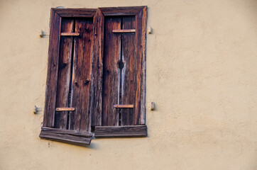 Window with old closed shutters in bright house wall. Copy Space for characters or letters.