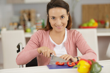 woman in wheelchair cutting pepers in the kitchen