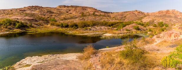 A view across the desert rock park towards the city fortifications in Jodhpur, Rajasthan, India