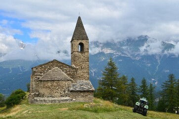 Saint-Pierre d'Extravache Church, fields and alpacas. in the background of the Vanoise National Park, France