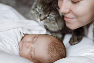 Adorable child in a white sunny bedroom. Baby is resting in bed. Family morning at home. Loving mom carying of her newborn baby.