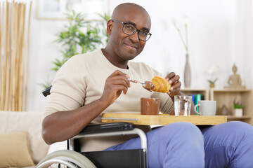 Fototapeta na wymiar handsome man in wheelchair having breakfast
