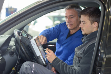 student with instructor repairing a car during apprenticeship