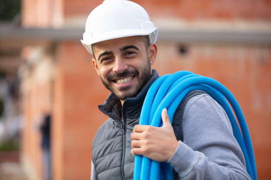 portrait of a smiling worker carrying corrugated conduit