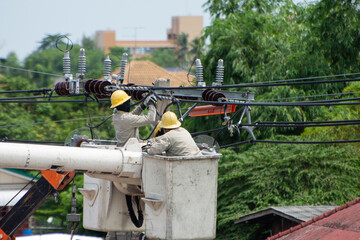 Electricity workers stand on the cable car for maintenance, maintenance of the high voltage line system. On the electric pole is dangerous thailand 06-08-2020