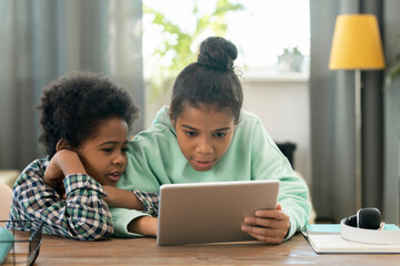 Cute elementary mixed-race siblings watching online educational video