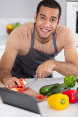 Fototapeta premium happy man cooking healthy food looking on digital tablet