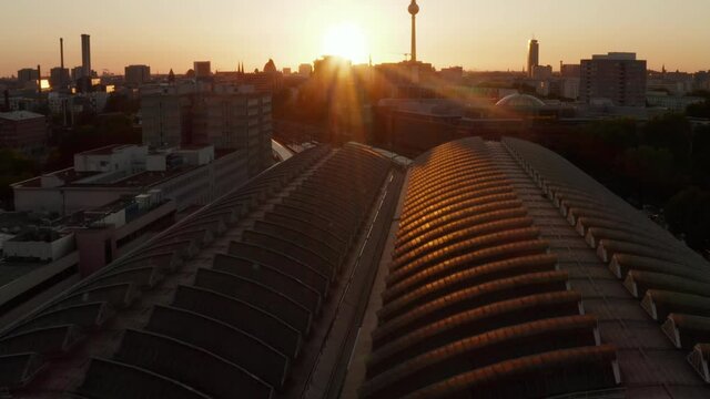 Scenic View of Ostbahnhof Central Train Station at beautiful Sunset, Sunlight and view on Alexanderplatz TV Tower, slow Aerial tilt up