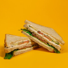 Tasty sandwich with white bread, tomato, onion, salad on yellow background. Isolated.	
