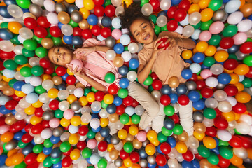 Fototapeta na wymiar High angle view of African children lying together in the pool and playing with colored balls
